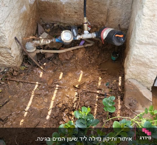 מד מים וצינור ליד קיר אבן